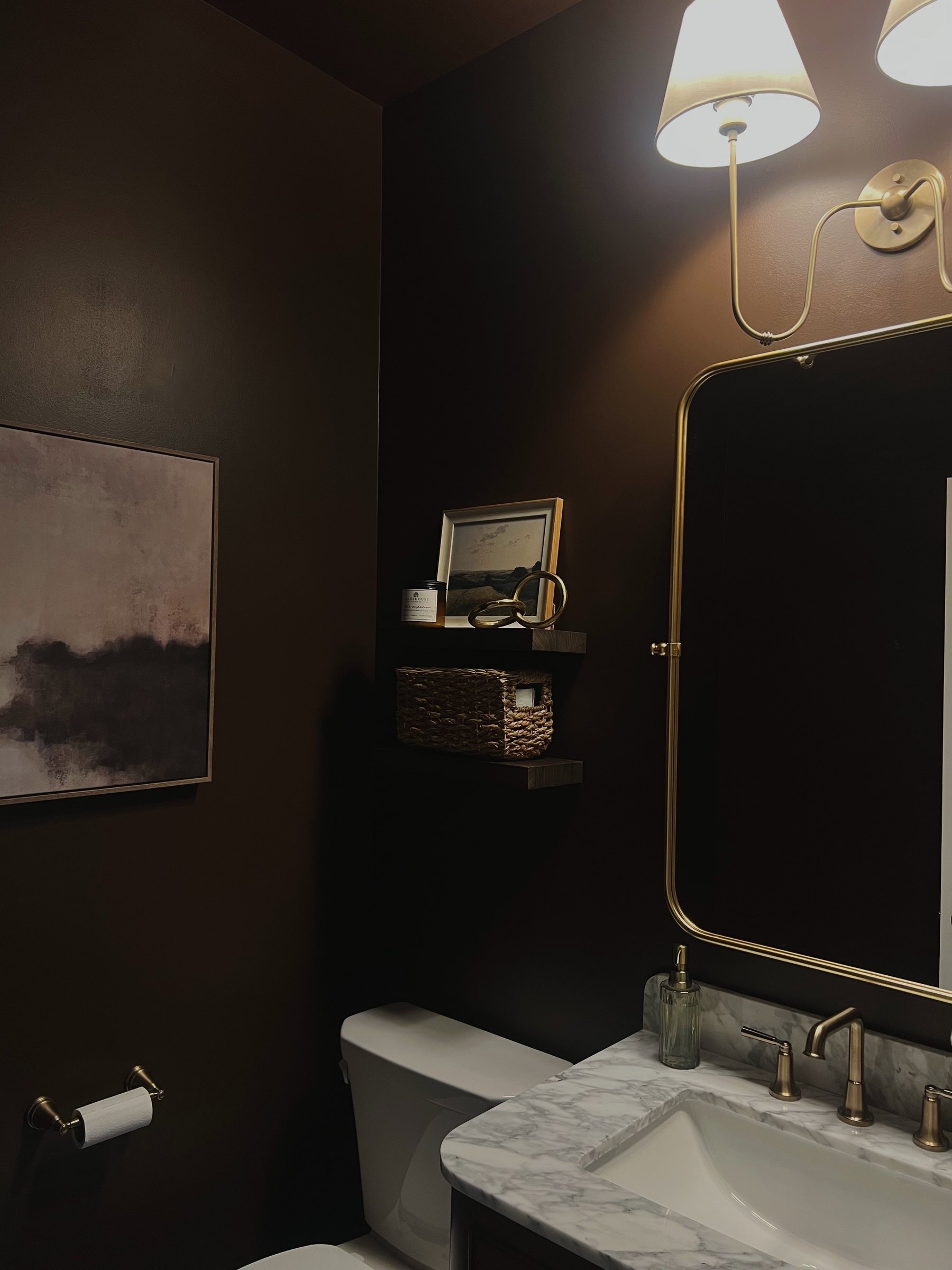 Moody powder room with brass fixtures and marble vanity