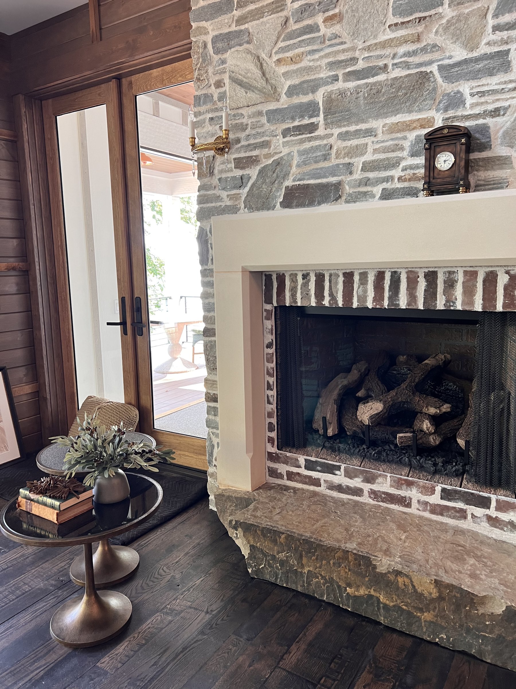 Stone fireplace with brass accents and French doors